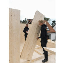 Drei Handwerker montieren eine Holzkonstruktion für ein Gebäude.