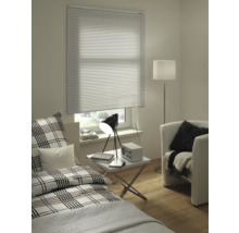 Wohnraum mit Bett, Sessel, Stehlampe, Tisch und Fenster mit Jalousie