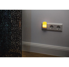 Nachtlicht in Steckdose neben dekorativer Lampe