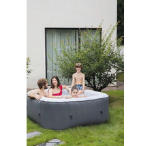 Familie entspannt in einem aufblasbaren Whirlpool im Garten.