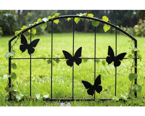 Dekorative Gartenpforte mit Schmetterlingsmotiven und Pflanzenverzierungen im Garten.