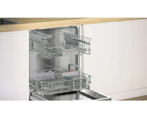 Geöffneter Geschirrspüler mit Geschirrkörben vor weißer Küchenfront