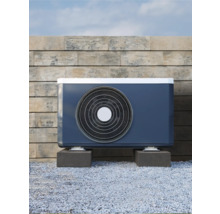 Außeneinheit einer Luft-Wasser-Wärmepumpe vor einer Steinmauer