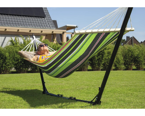 Mann entspannt in einer gestreiften Hängematte mit Gestell im Garten.
