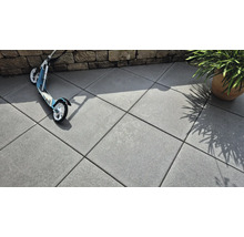 Verlegte Betonsteine im Außenbereich mit Roller und Pflanze