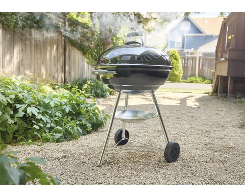 Kugelgrill im Garten mit Rauchentwicklung.