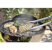 Grill mit Hähnchenbrust und Grillzange.
