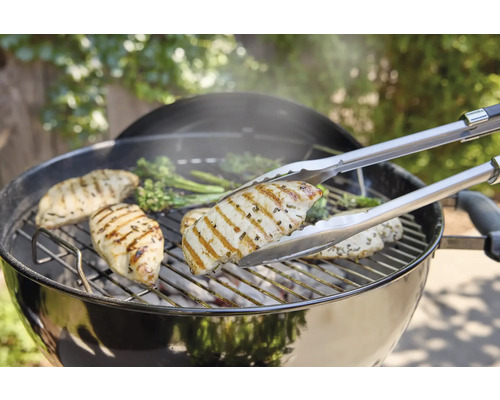 Grill mit Hähnchenbrust und Grillzange.