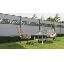 Gartenszene mit Betonzäunen, Rattansesseln und Beistelltisch auf einer Rasenfläche.