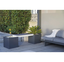 Gartenmöbelanordnung mit Pflanzgefäßen, die als Bank dienen, und einem Sofa auf einer Terrasse.