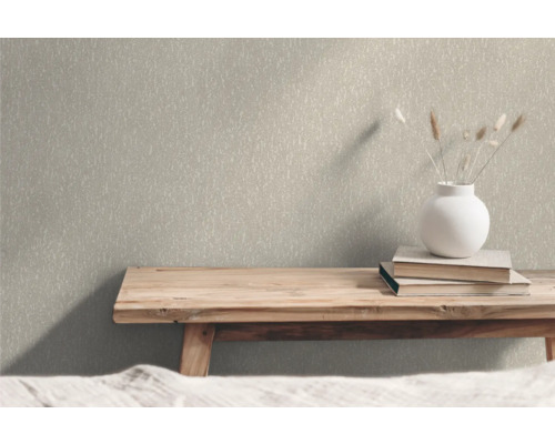 Nahaufnahme einer strukturierten Tapete im Innenraum mit Holzbank, Büchern und Blumenvase als Dekoration.