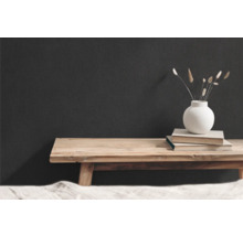 Dekorative Szene mit Holzbank, Büchern und Vase mit getrockneten Blumen vor dunkler Wand