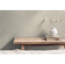 Dekorative Szene mit Holzbank, Büchern und Vase mit Gräsern vor einer Wand.