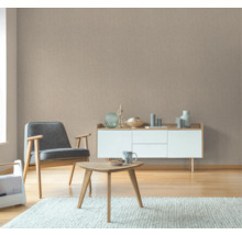 Wohnzimmer mit Sessel, Tisch und Sideboard vor einer Strukturtapete