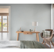 Helles Schlafzimmer mit Holztisch, Lampe und Stuhl.