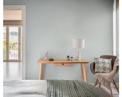 Helles Schlafzimmer mit Holztisch, Lampe und Stuhl.