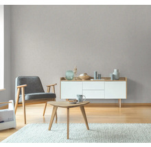 Wohnzimmer mit Sessel, Tisch und Sideboard vor einer grauen Tapete
