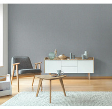 Wohnzimmer mit grauer Strukturtapete, Sessel, Kommode und Tisch