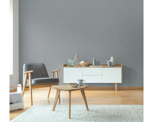 Wohnzimmer mit grauer Strukturtapete, Sessel, Kommode und Tisch