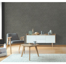 Wohnzimmer mit Sessel, Beistelltisch und Kommode vor einer strukturierten Wandtapete.