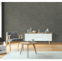 Wohnzimmer mit grauer gemusterter Tapete, Sessel, Sideboard und Tisch auf Teppich