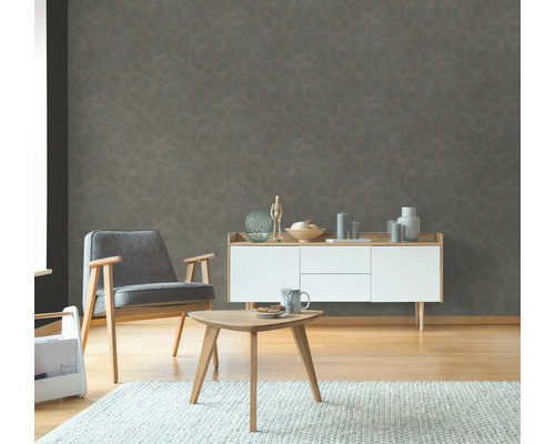 Wohnzimmer mit grauer gemusterter Tapete, Sessel, Sideboard und Tisch auf Teppich