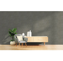Wohnzimmer mit grauer Strukturwand, Sessel, Pflanze und Kommode