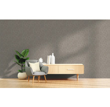 Wohnzimmer mit grauer gemusterter Tapete, Sessel, Pflanze und Sideboard.