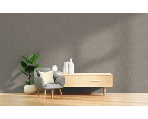 Wohnzimmer mit grauer gemusterter Tapete, Sessel, Pflanze und Sideboard.