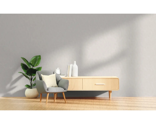 Wohnzimmer mit Sessel, Zimmerpflanze und Holzkommode