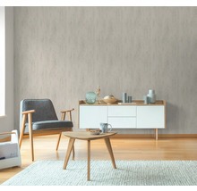 Wohnraum mit gemusterter Tapete, Sessel, Tisch und Kommode für ein gemütliches Ambiente