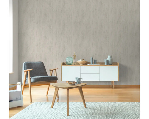 Wohnraum mit gemusterter Tapete, Sessel, Tisch und Kommode für ein gemütliches Ambiente