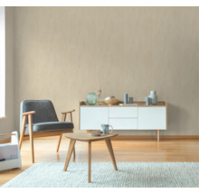 Wohnzimmer mit Sessel, Tisch und Sideboard vor einer beigen Wand