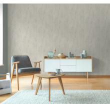 Wohnzimmer mit gemusterter Tapete, Sessel, Tisch und Kommode