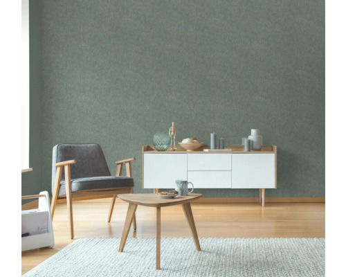 Wohnzimmer mit Sessel, Beistelltisch und Kommode vor einer grünen Wandtapete