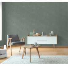 Wohnzimmer mit grüner Struktur-Tapete, Sessel, Tisch und Sideboard