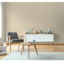 Wohnzimmer mit Sessel, Couchtisch und Sideboard vor einer gemusterten Tapete