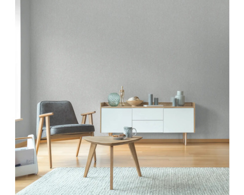 Wohnzimmer mit Sessel, Beistelltisch und Sideboard vor einer strukturierten Tapete