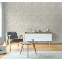 Wohnzimmer mit blattgemusterter Tapete, Sessel, Tisch und Sideboard