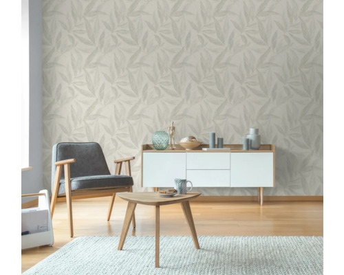 Wohnzimmer mit blattgemusterter Tapete, Sessel, Tisch und Sideboard