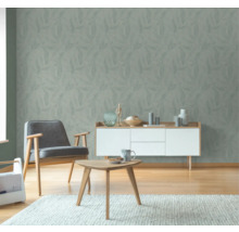 Wohnzimmer mit Blattmuster-Tapete, Sessel, Kommode und Tisch auf Teppich