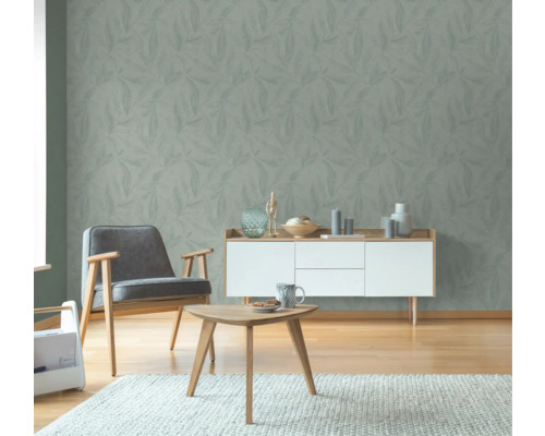 Wohnzimmer mit Blattmuster-Tapete, Sessel, Kommode und Tisch auf Teppich