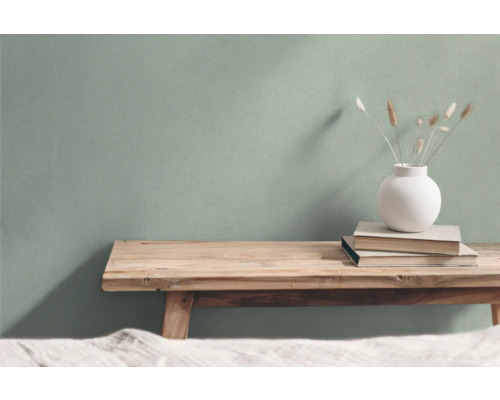 Wohnszene mit Holzbank, Büchern und Vase vor einer Wand
