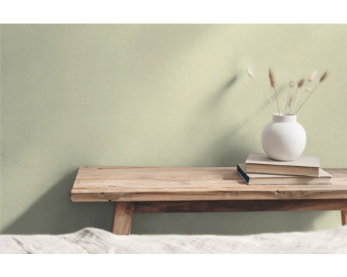 Wohnraum mit Holzhocker, Bücherstapel und Blumenvase