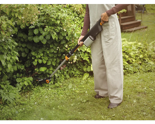 Person benutzt Akku-Grasschere zur Gartenarbeit