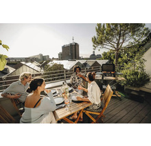 Personen grillen und essen auf einer Dachterrasse mit Stadtblick