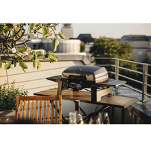 Gasgrill auf einem Balkon mit einem Holztisch und Stühlen