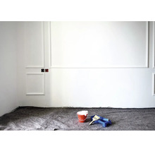 Renovierungsarbeiten mit Farbeimer, Pinsel und Farbroller vor weißer Wand mit Stuckelementen