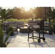 Gartenszene mit Holzkohlegrill, Sitzgruppe und Feuerstelle für eine gemütliche Atmosphäre im Freien.