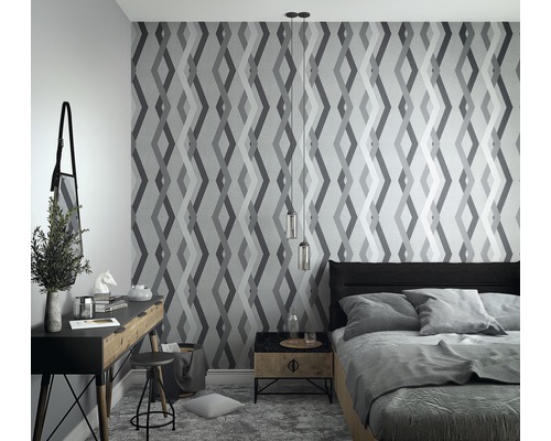 Schlafzimmer mit geometrischer Tapete, Bett, Schreibtisch und Nachttisch